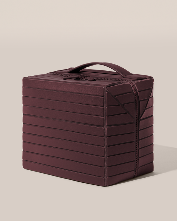 Side view of the closed Afform Large Cassis (maroon) Kit toiletry bag with a compact, zip-around design and top handle for elevated everyday or travel organization