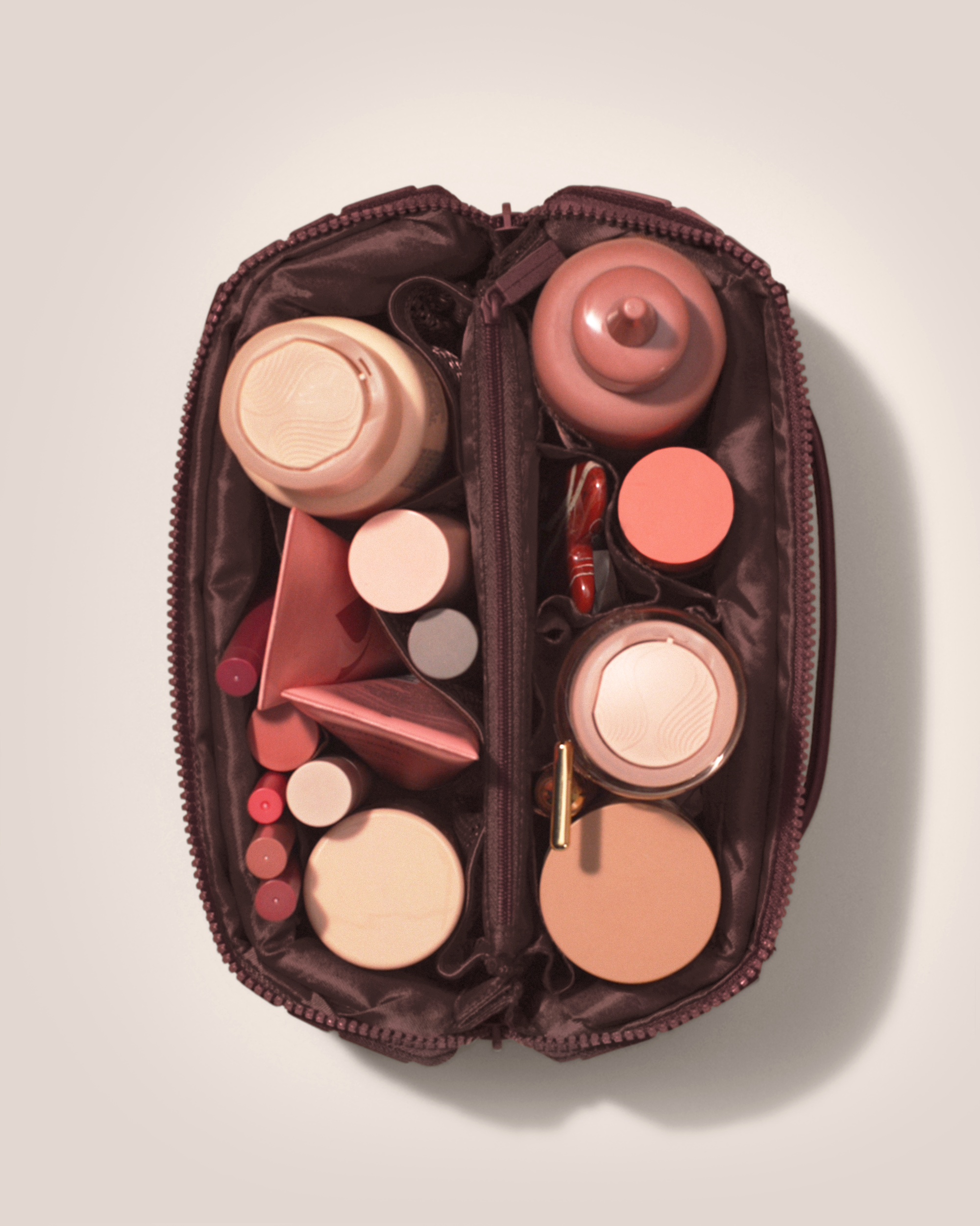 Overhead view of Afform Cassis (maroon) Kit toiletry bag fully packed with upright toiletry products and organized compartments