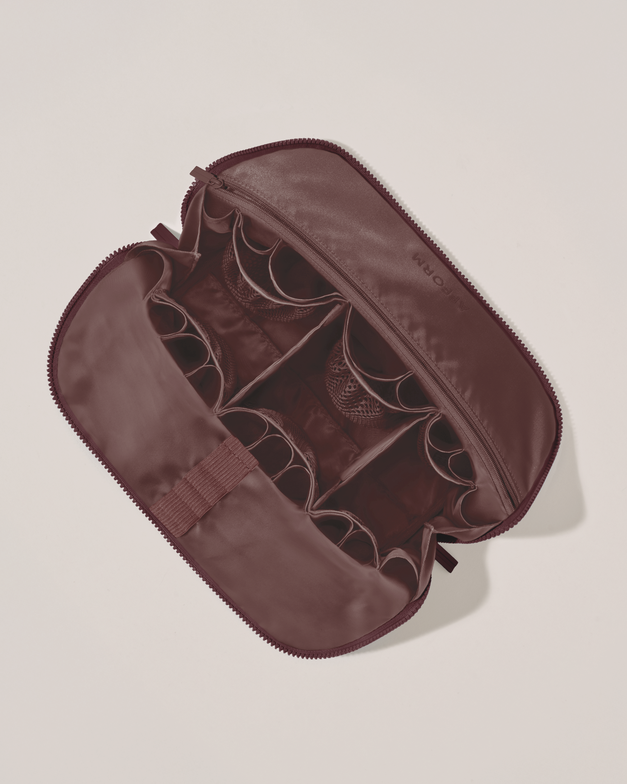 Interior view of Afform Large Cassis (maroon) Traveller makeup bag showing empty pockets, pouches, elastic holders, and zipper pocket for loose items