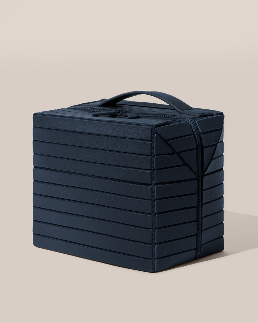 Side view of the closed Afform Large Indigo (blue) Kit toiletry bag with a compact, zip-around design and top handle for elevated everyday or travel organization