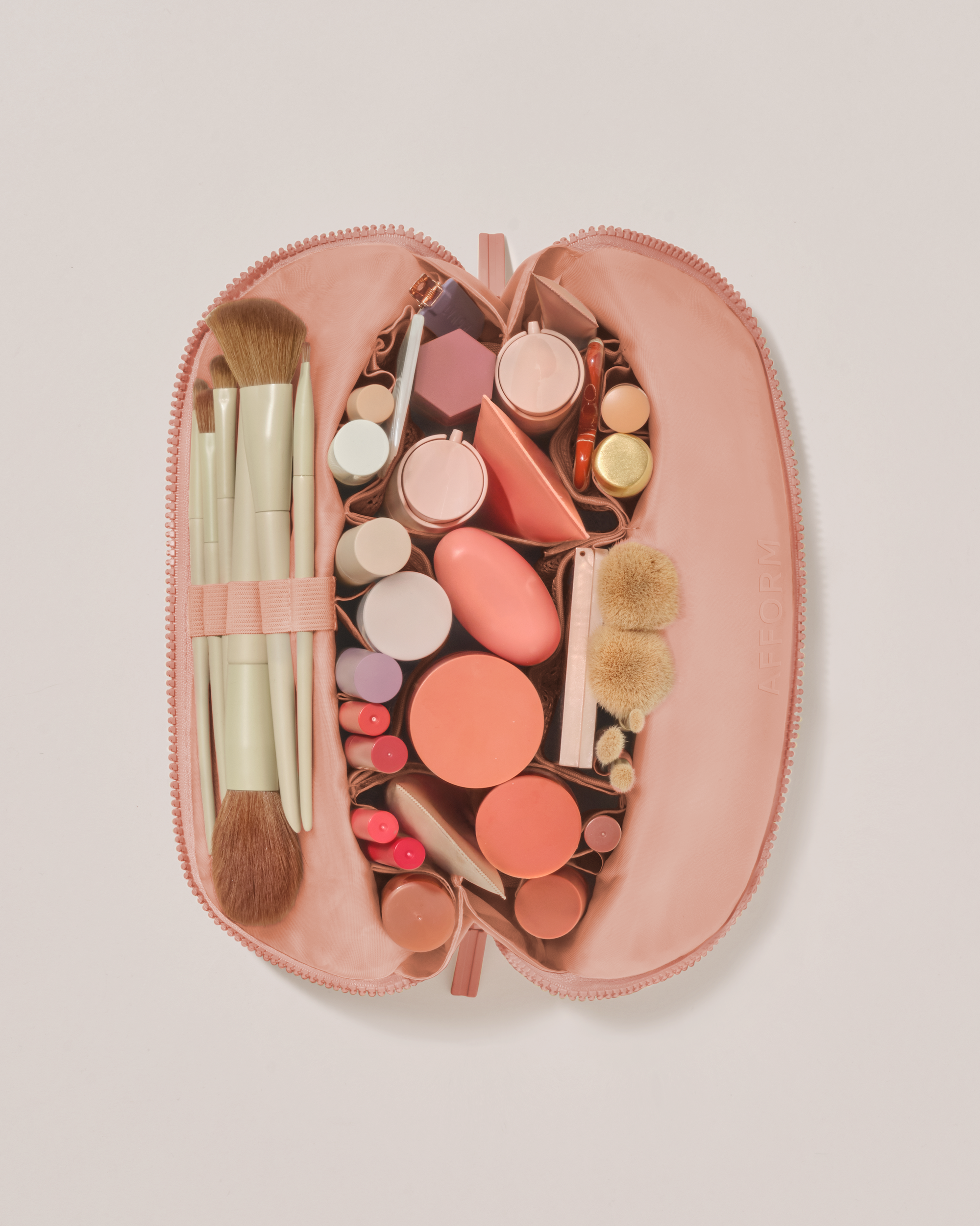 Overhead view of the Medium Blush (pink) Traveller makeup bag fully packed with upright beauty products and organized compartments