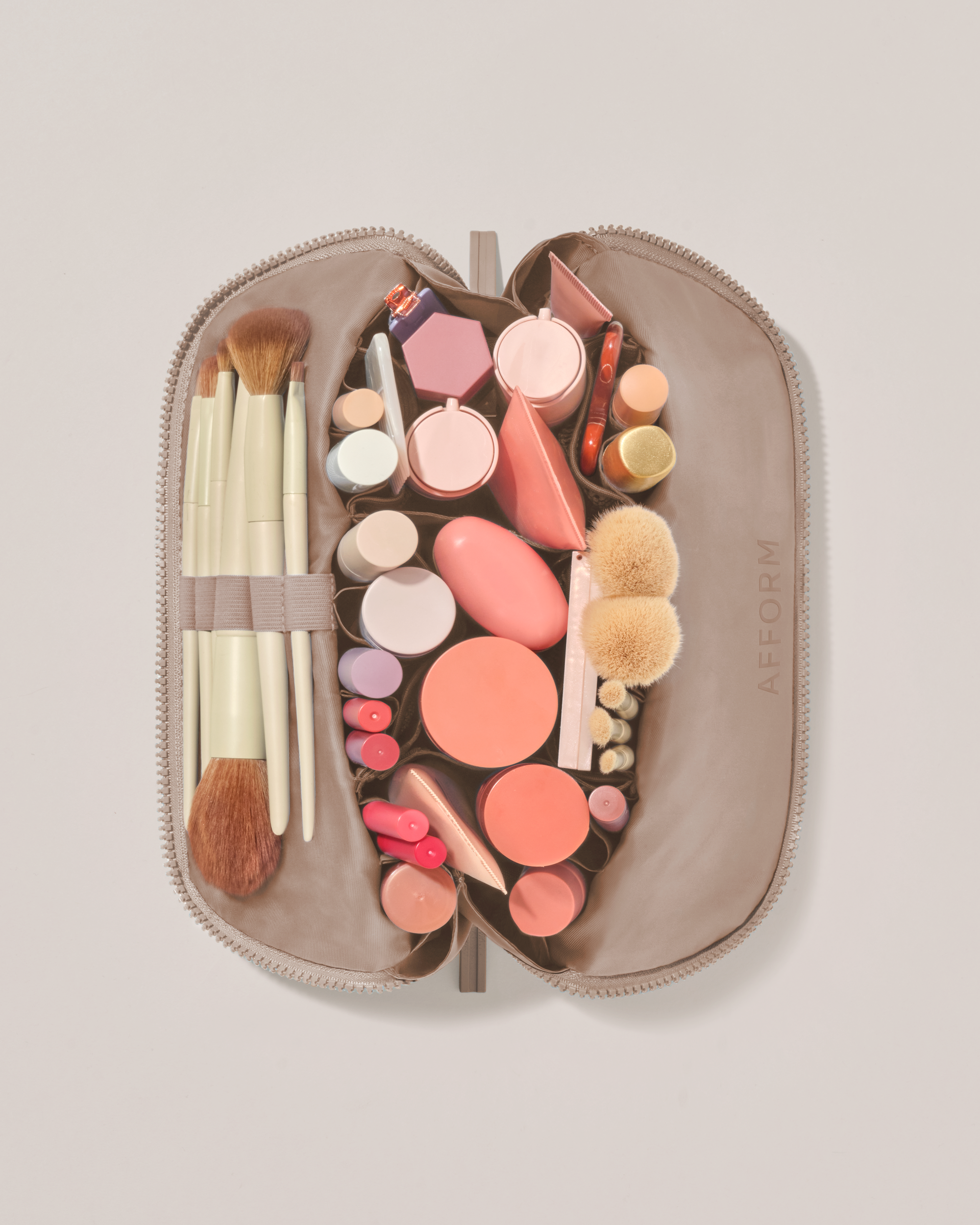 Overhead view of the Medium Bronze Traveller makeup bag fully packed with upright beauty products and organized compartments