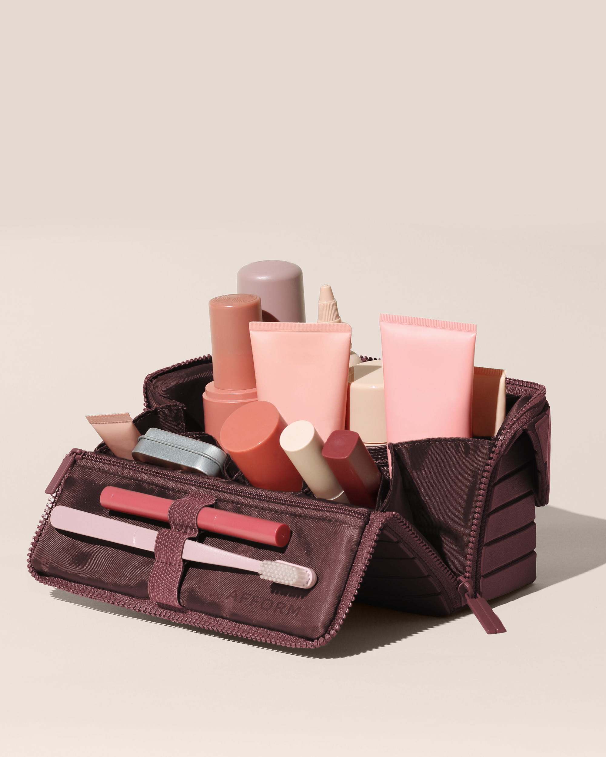 Open Afform Medium Cassis (maroon) Kit, shown open and packed with skincare and grooming products and expanded using its accordion opening