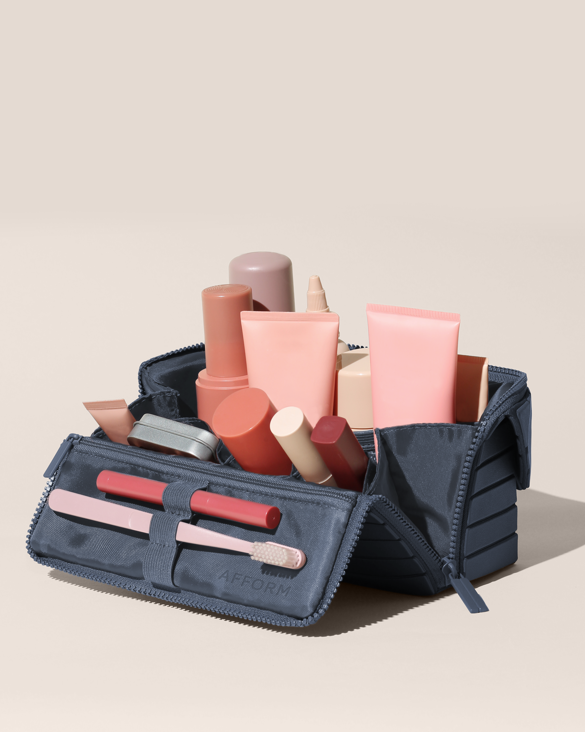 Open Afform Medium Indigo (blue) Kit, shown open and packed with skincare and grooming products and expanded using its accordion opening