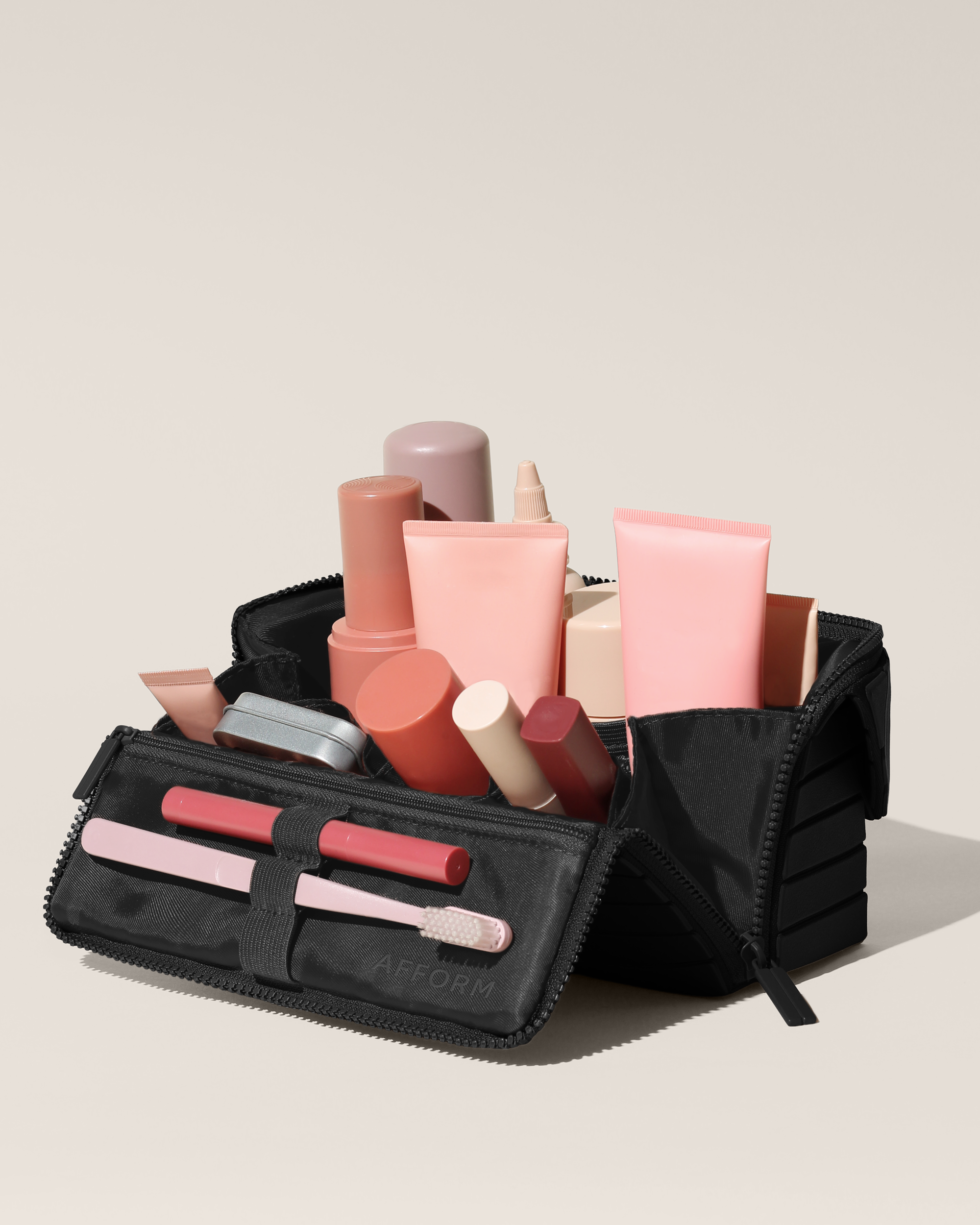 Open Afform Medium Onyx (black) Kit, shown open and packed with skincare and grooming products and expanded using its accordion opening