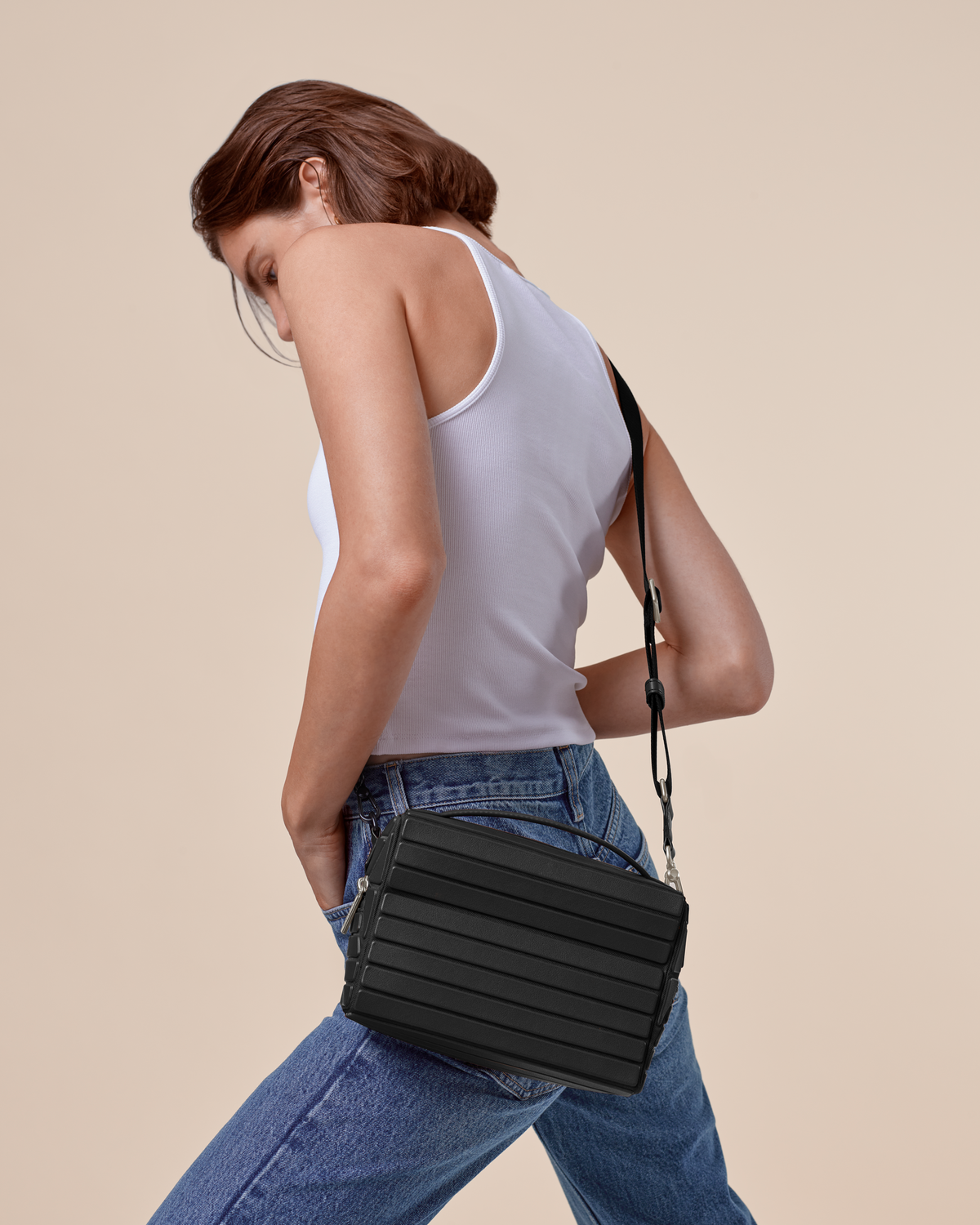 Model wearing the Onyx Crossbody bag with a white tank top and jeans, showing the adjustable strap