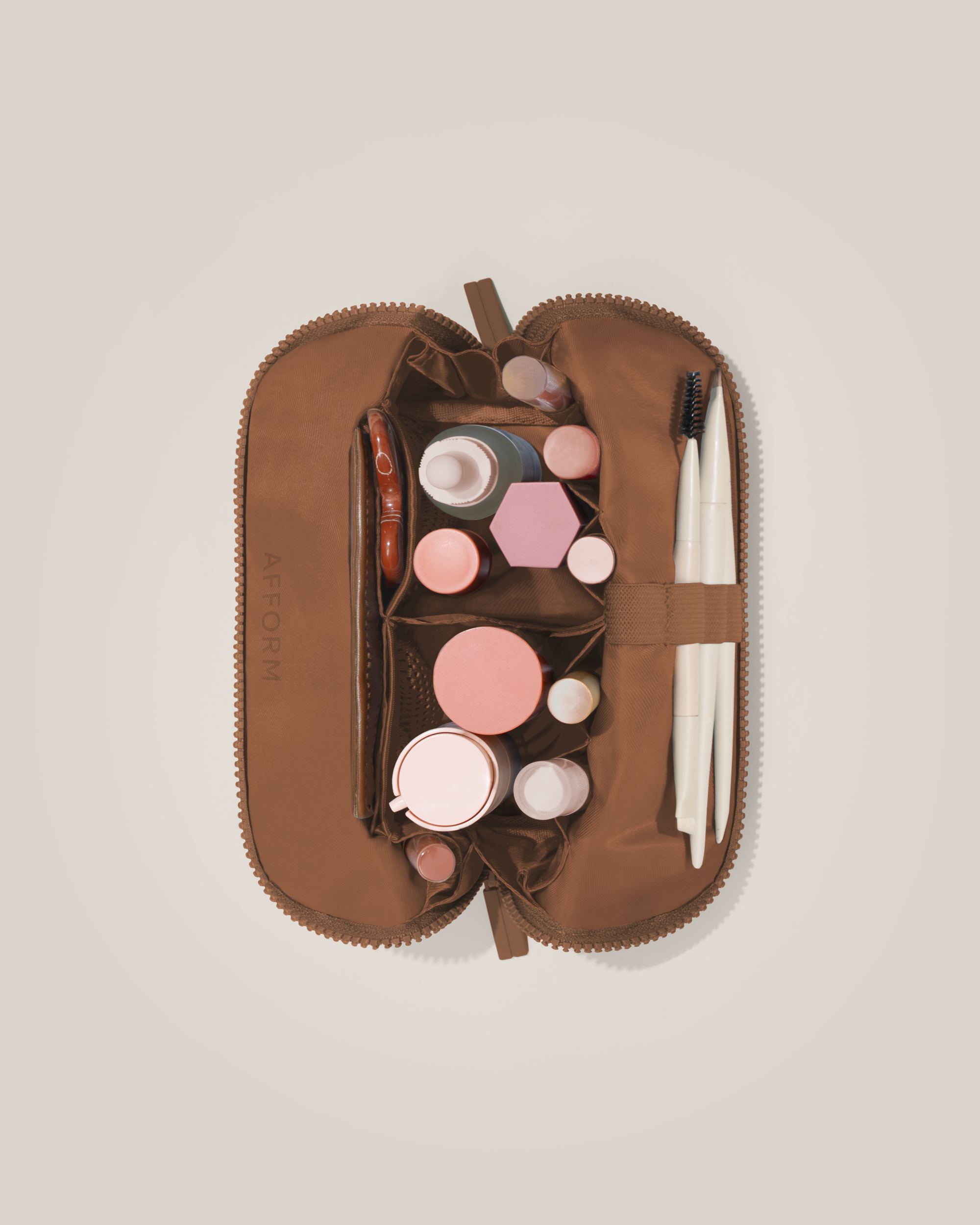 Overhead view of the Small Vicuna (brown) Traveller makeup bag fully packed with upright beauty products and organized compartments
