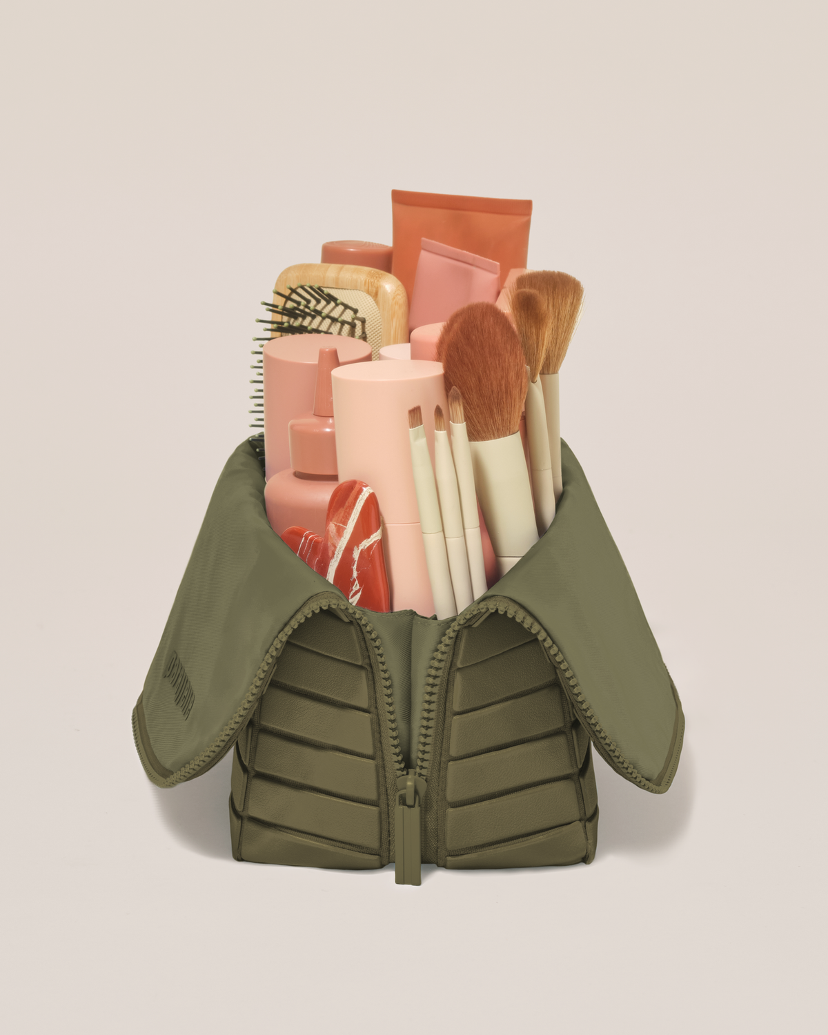 Side profile of the Large Olive (green) Traveller makeup bag filled with beauty essentials standing upright, showing flexible compartment design