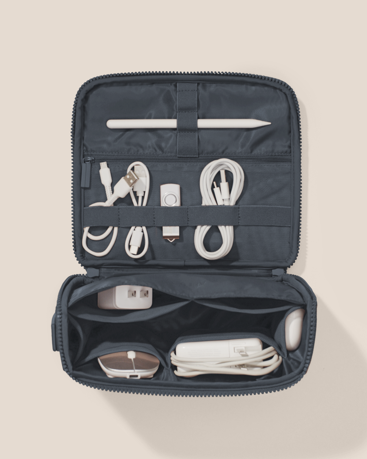 Overhead view of the Afform Indigo (navy) Tech Kit electronics organizer open and packed, showing cables, USB drives, and a stylus organized across 8 elastic loops and 6 mesh pockets on the upper panel, with a charger, mouse, and power bank in the structured lower compartment