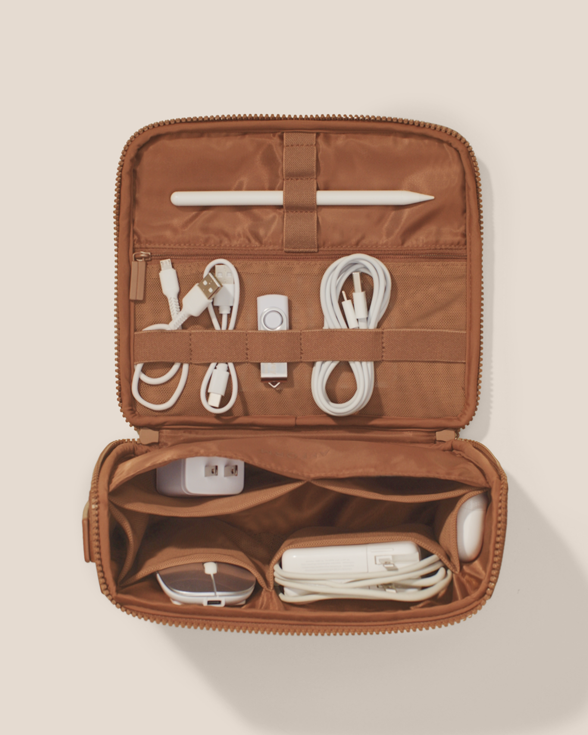 Overhead view of the Afform vicuna (brown) Tech Kit electronics organizer open and packed, showing cables, USB drives, and a stylus organized across 8 elastic loops and 6 mesh pockets on the upper panel, with a charger, mouse, and power bank in the structured lower compartment