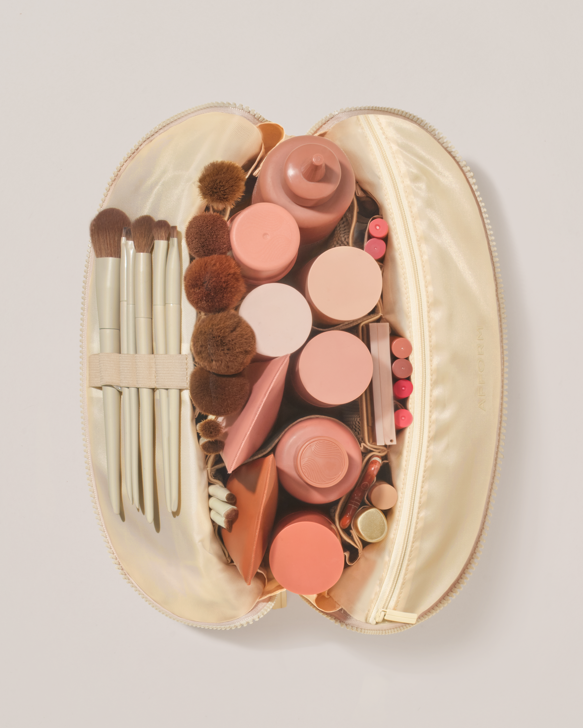 Overhead view of the Large Bisque (white) Traveller makeup bag fully packed with upright beauty products and organized compartments
