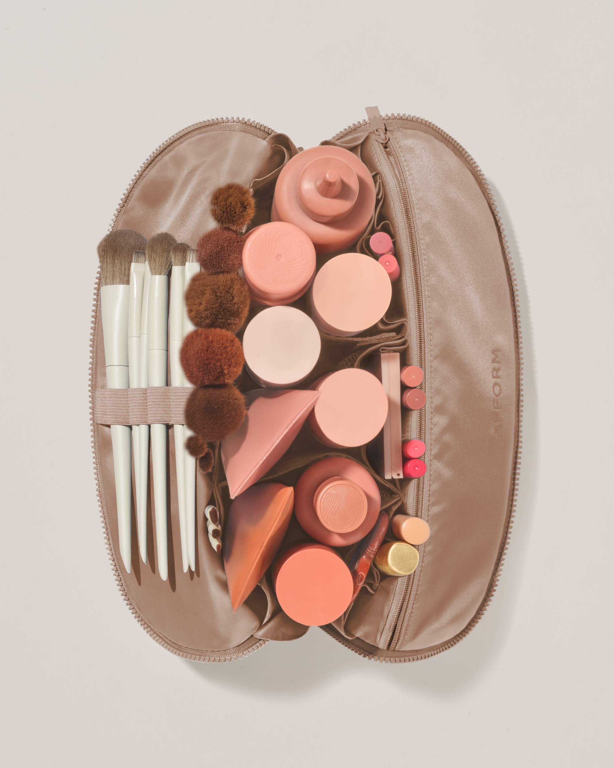 Overhead view of the Large Bronze Traveller makeup bag fully packed with upright beauty products and organized compartments