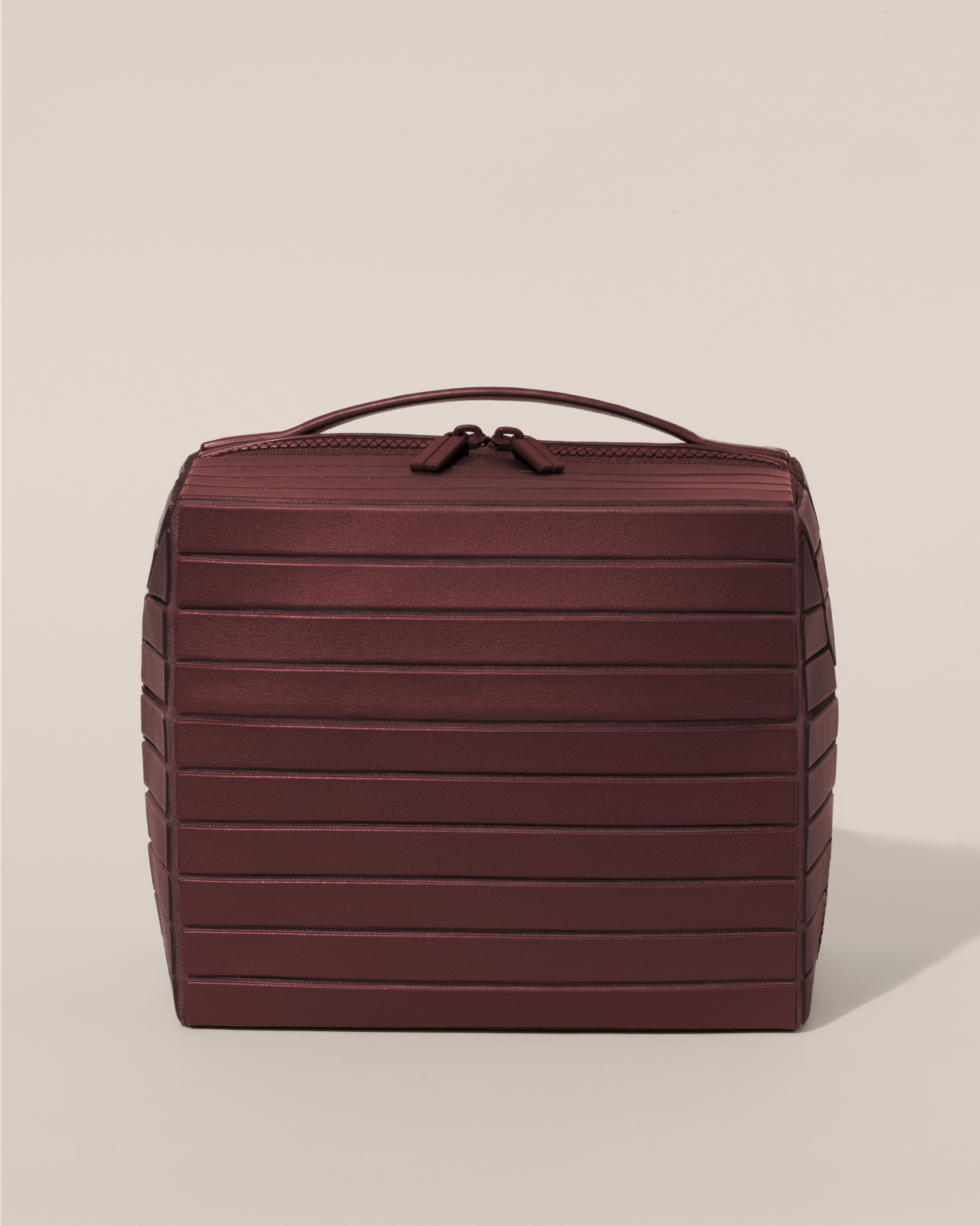 Front view of the closed Afform Large Cassis (maroon) Kit toiletry bag with a compact, zip-around design and top handle for elevated everyday or travel organization