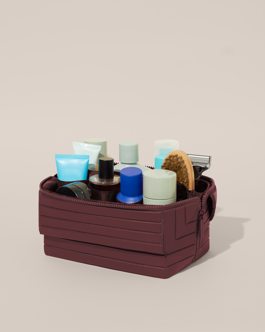 Open Afform Large Cassis (maroon) Kit, shown open and packed with grooming essentials like razors, cologne, and skincare. A structured, travel-ready toiletry organizer