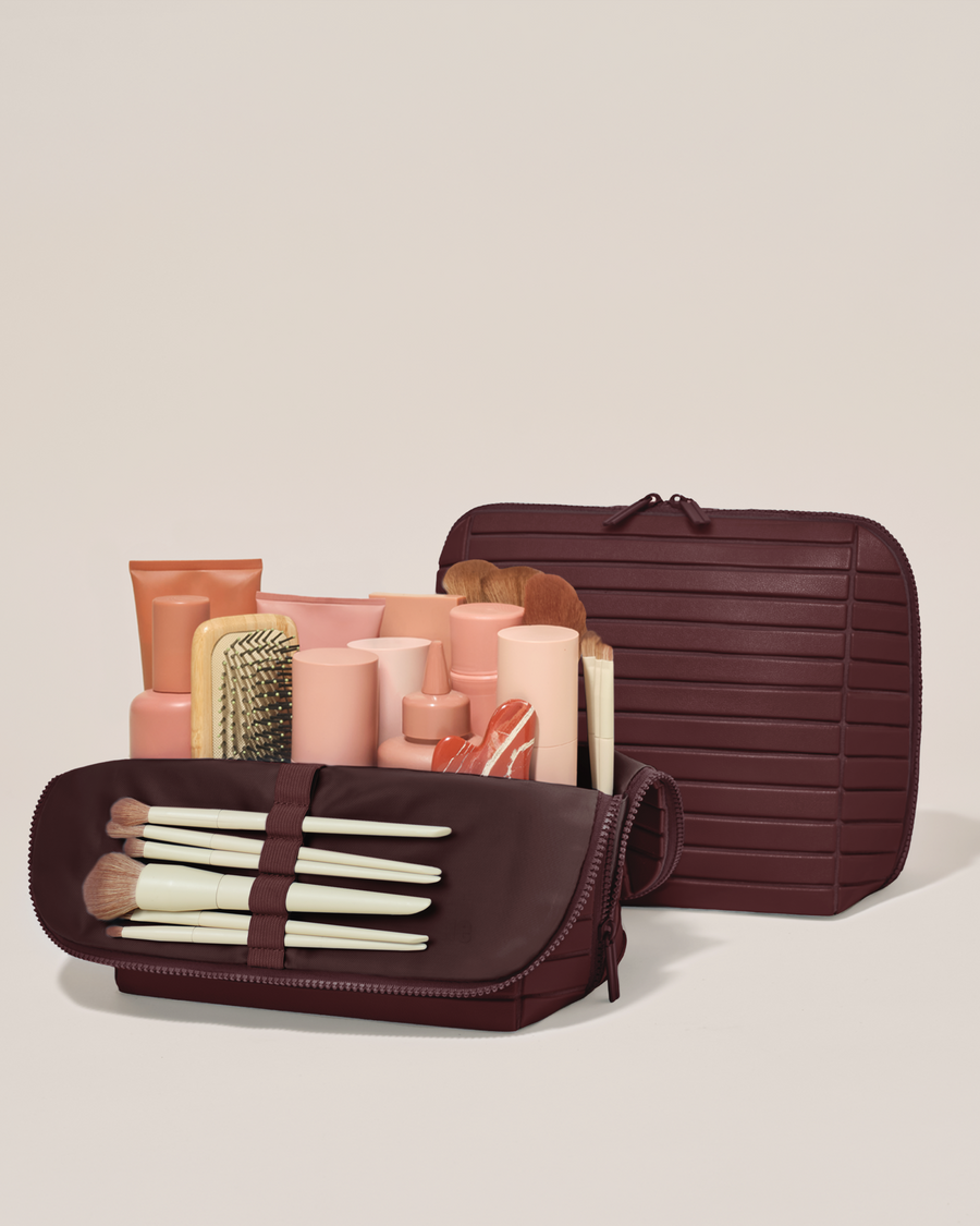 Open and closed Afform Large Cassis (maroon) Traveller makeup bag showing skincare, brushes, and curated travel essentials