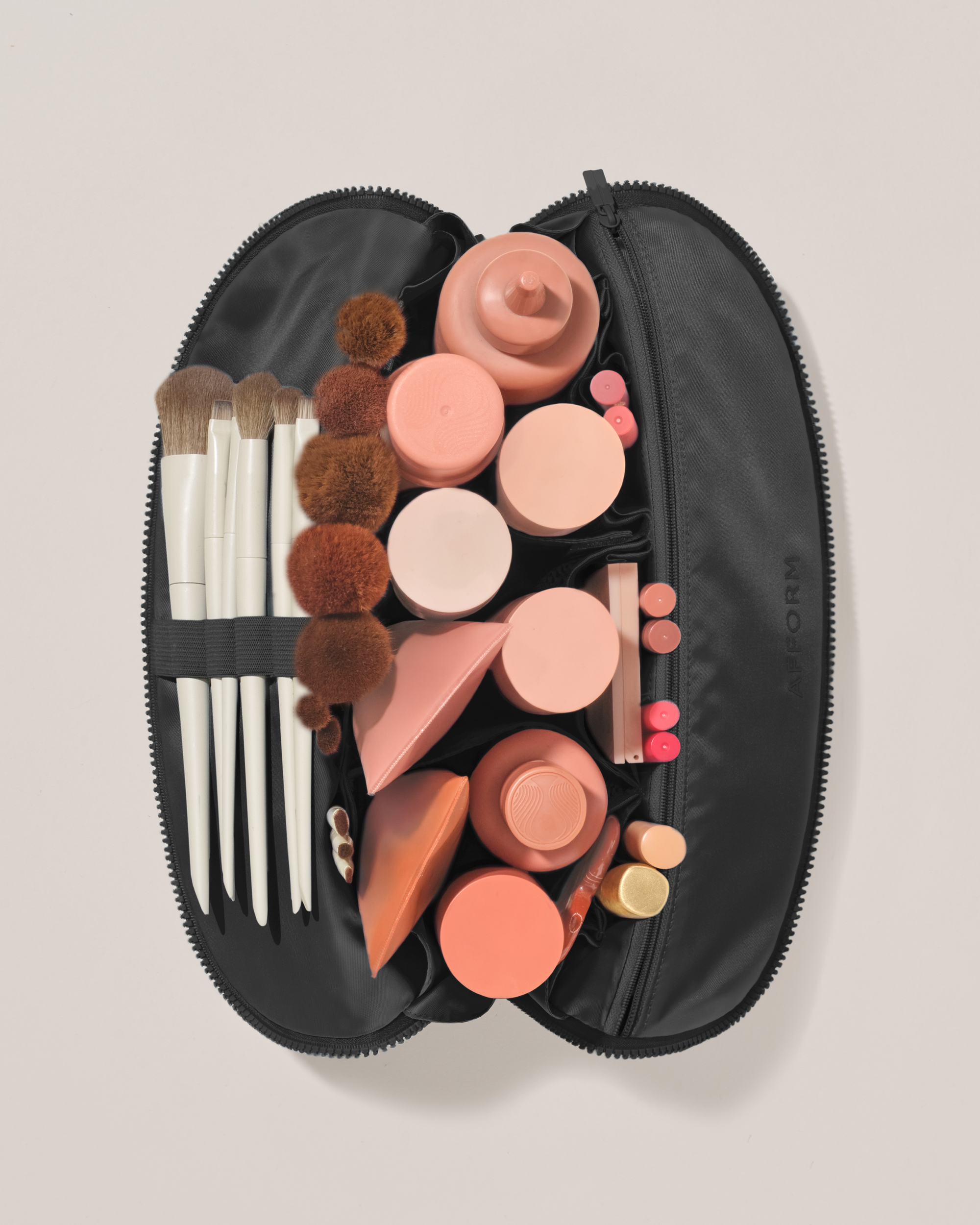 Overhead view of the Large Onyx (black) Traveller makeup bag fully packed with upright beauty products and organized compartments