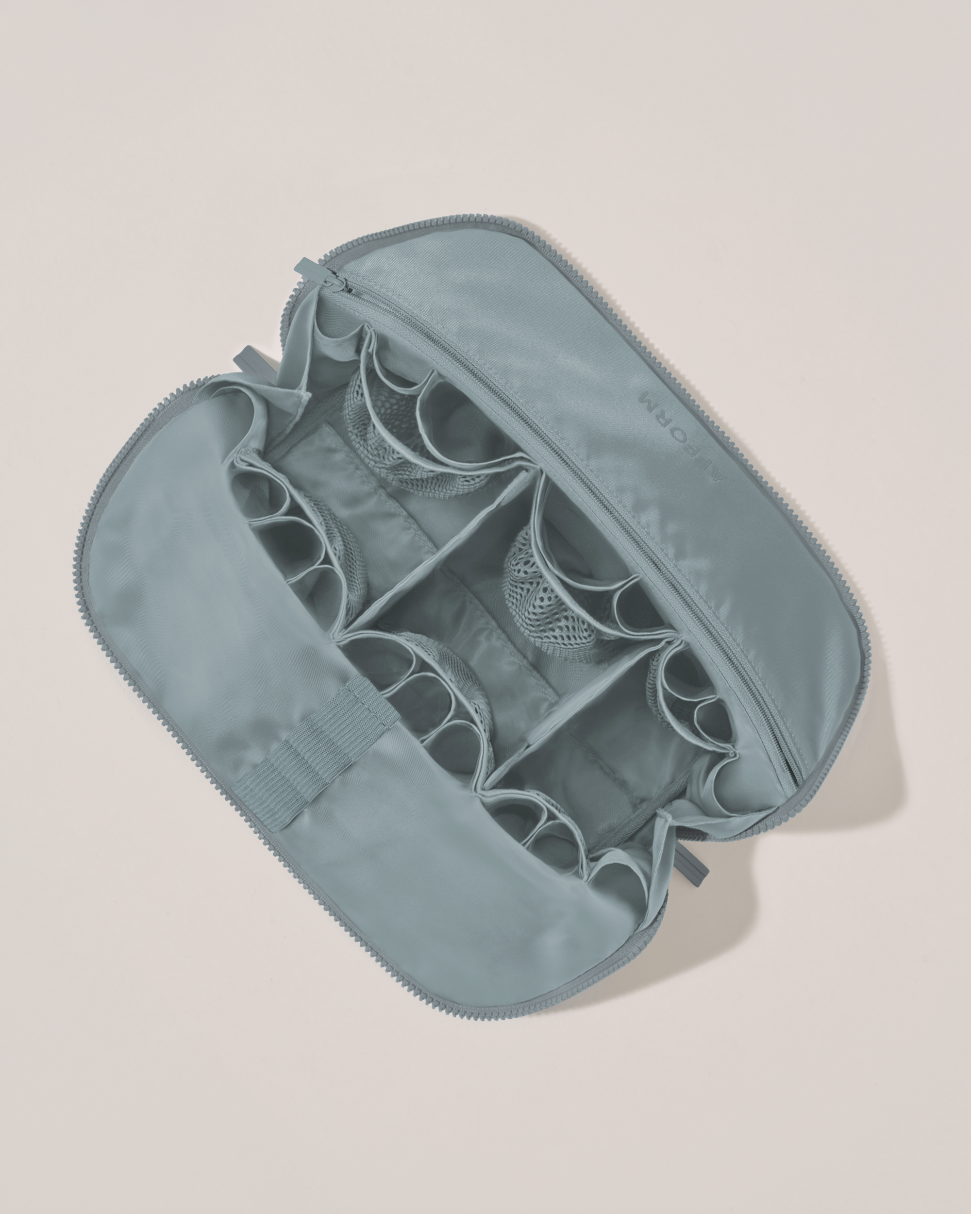 Interior view of Afform Large Slate (blue) Traveller makeup bag showing empty pockets, pouches, elastic holders, and zipper pocket for loose items