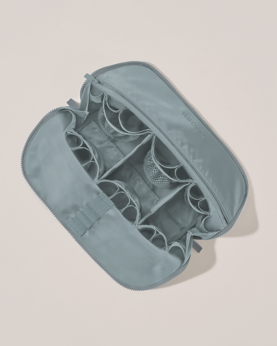 Interior view of Afform Large Slate (blue) Traveller makeup bag showing empty pockets, pouches, elastic holders, and zipper pocket for loose items