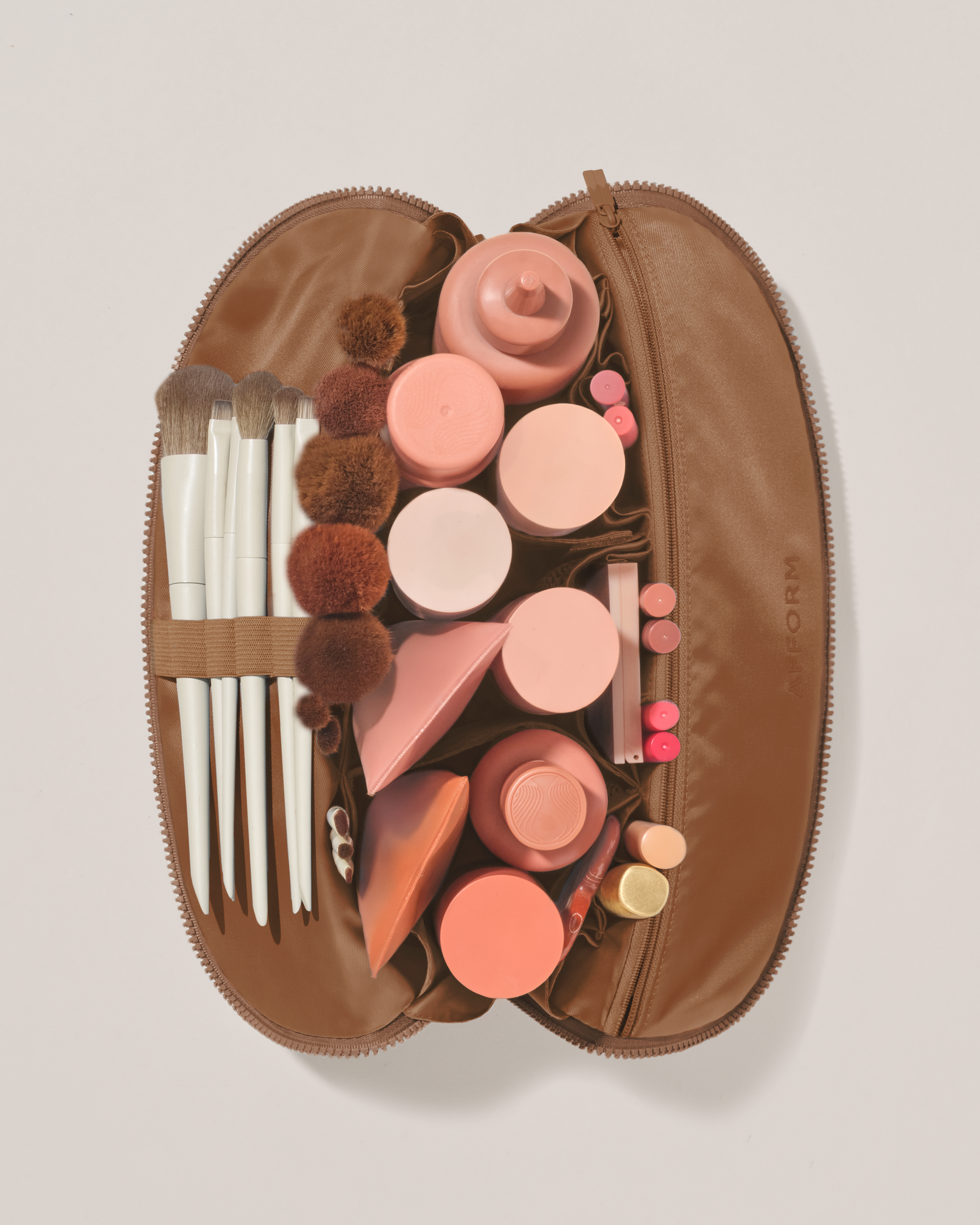 Overhead view of the Large Vicuna (brown) Traveller makeup bag fully packed with upright beauty products and organized compartments