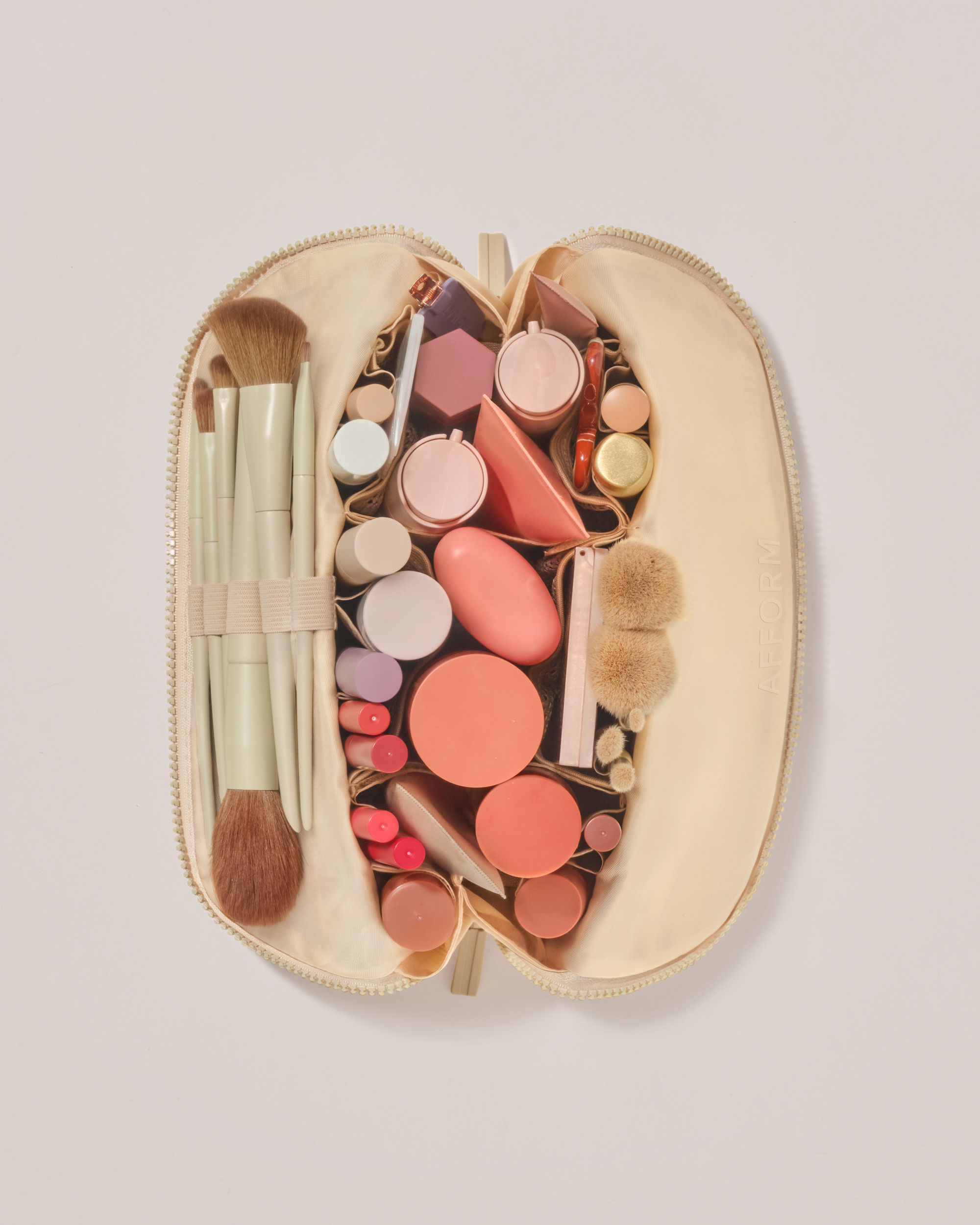 Overhead view of the Medium Bisque (white) Traveller makeup bag fully packed with upright beauty products and organized compartments