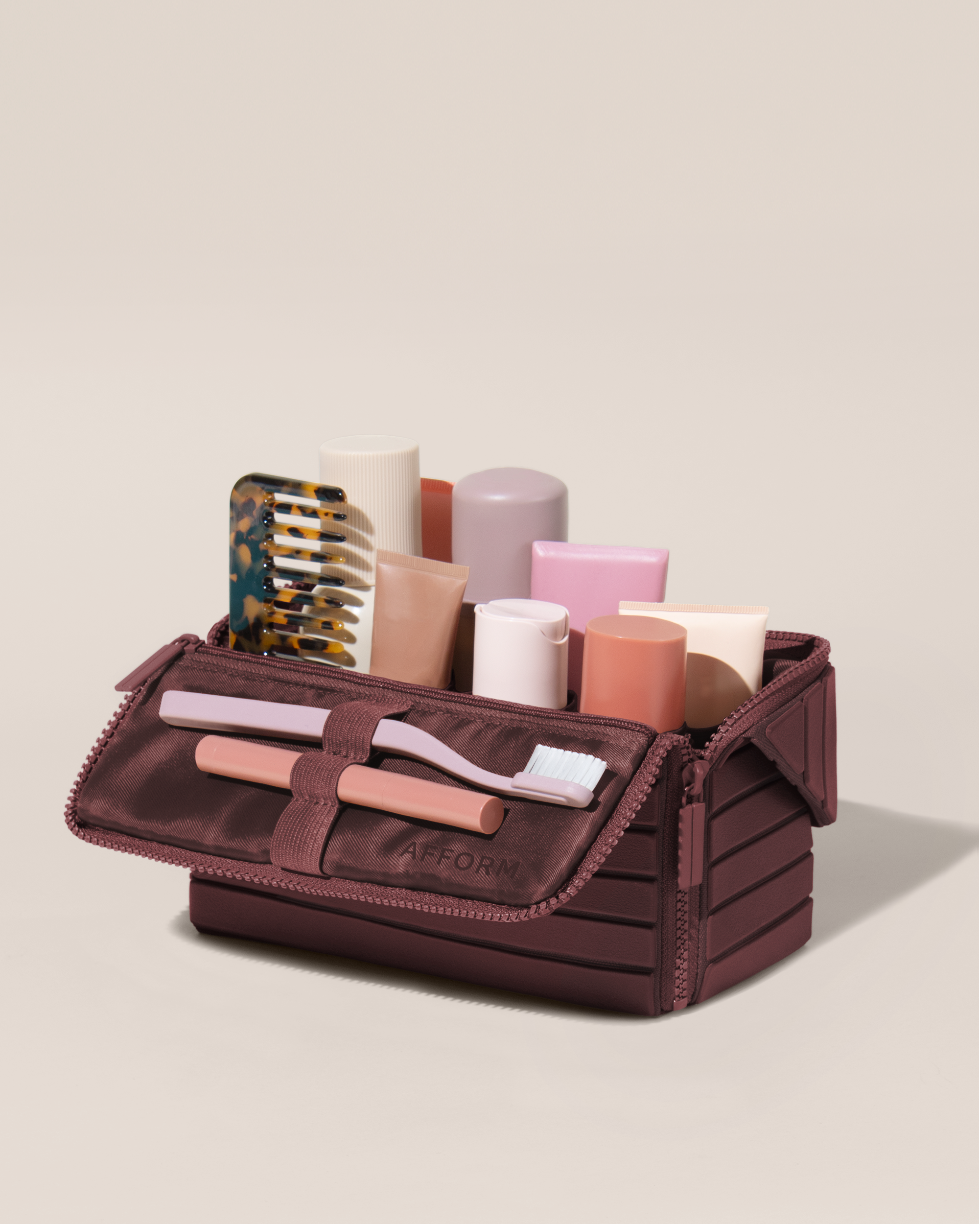 Open Afform Medium Cassis (maroon) Kit, shown open and packed with skincare and grooming products. A compact, structured toiletry bag designed for visibility and access.
