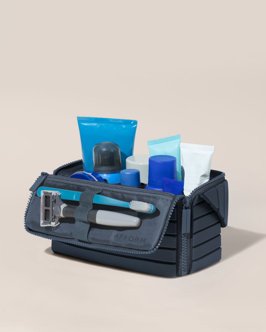 Open Afform Medium Indigo (blue) Kit, shown open and packed with grooming essentials like razors, cologne, and skincare. A structured, travel-ready toiletry organizer