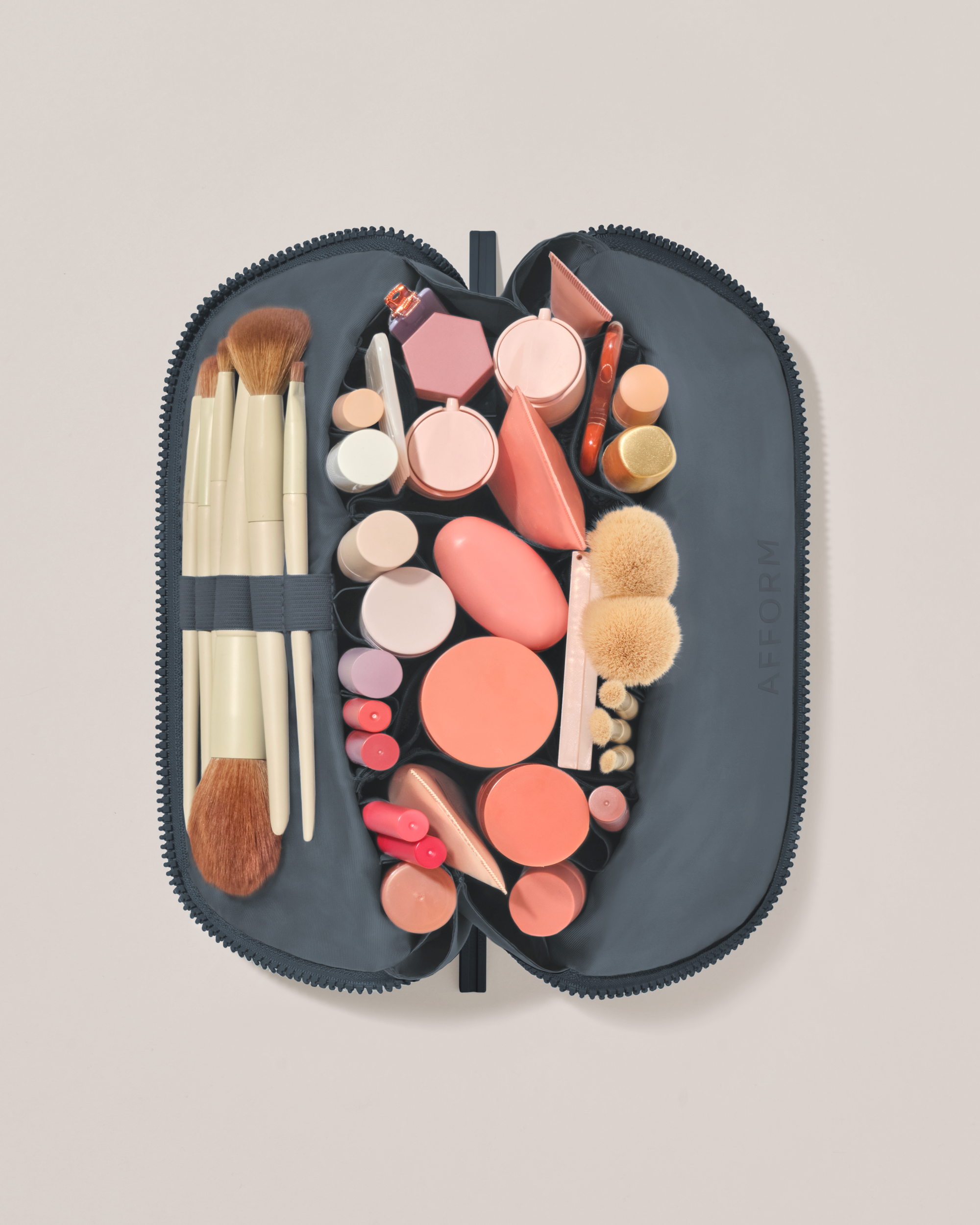 Overhead view of the Medium Indigo (navy) Traveller makeup bag fully packed with upright beauty products and organized compartments