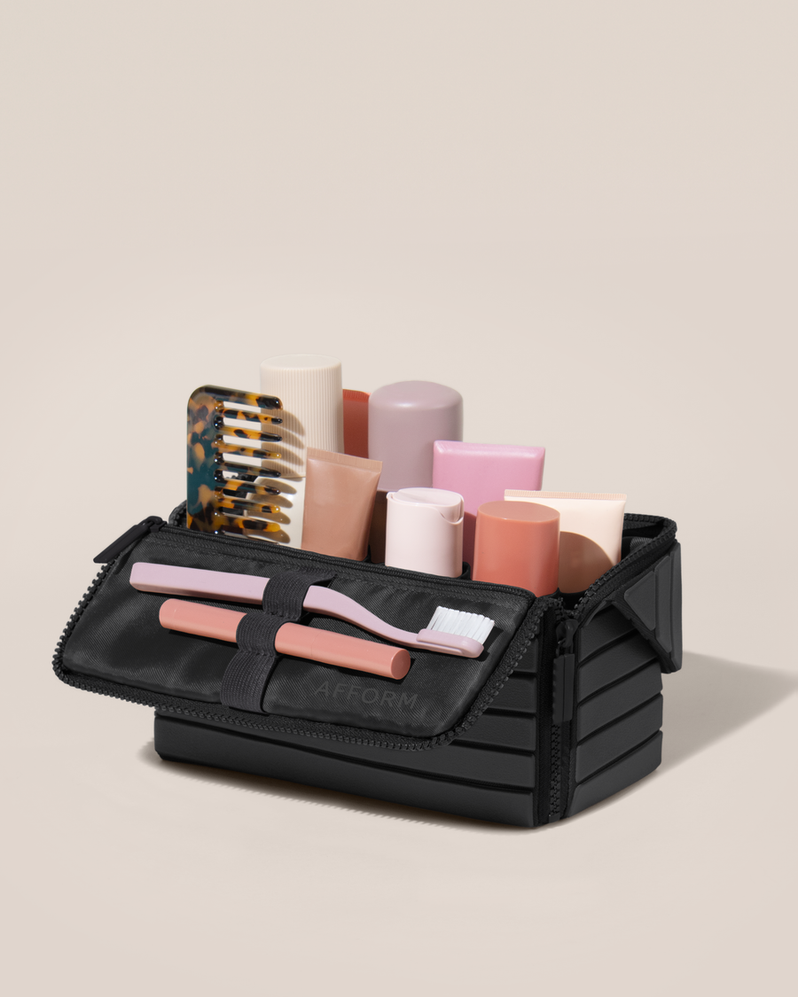 Open Afform Medium Onyx (black) Kit, shown open and packed with skincare and grooming products. A compact, structured toiletry bag designed for visibility and access.
