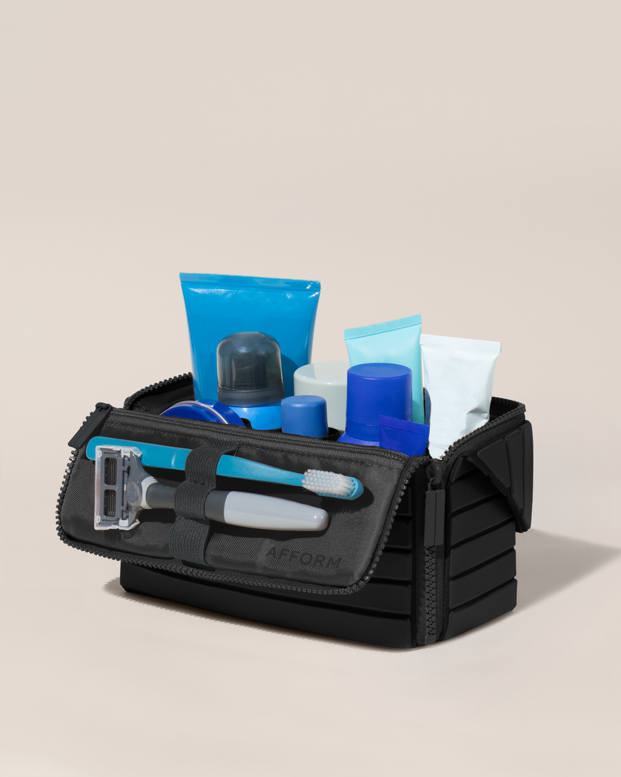 Open Afform Medium Onyx (black) Kit, shown open and packed with grooming essentials like razors, cologne, and skincare. A structured, travel-ready toiletry organizer