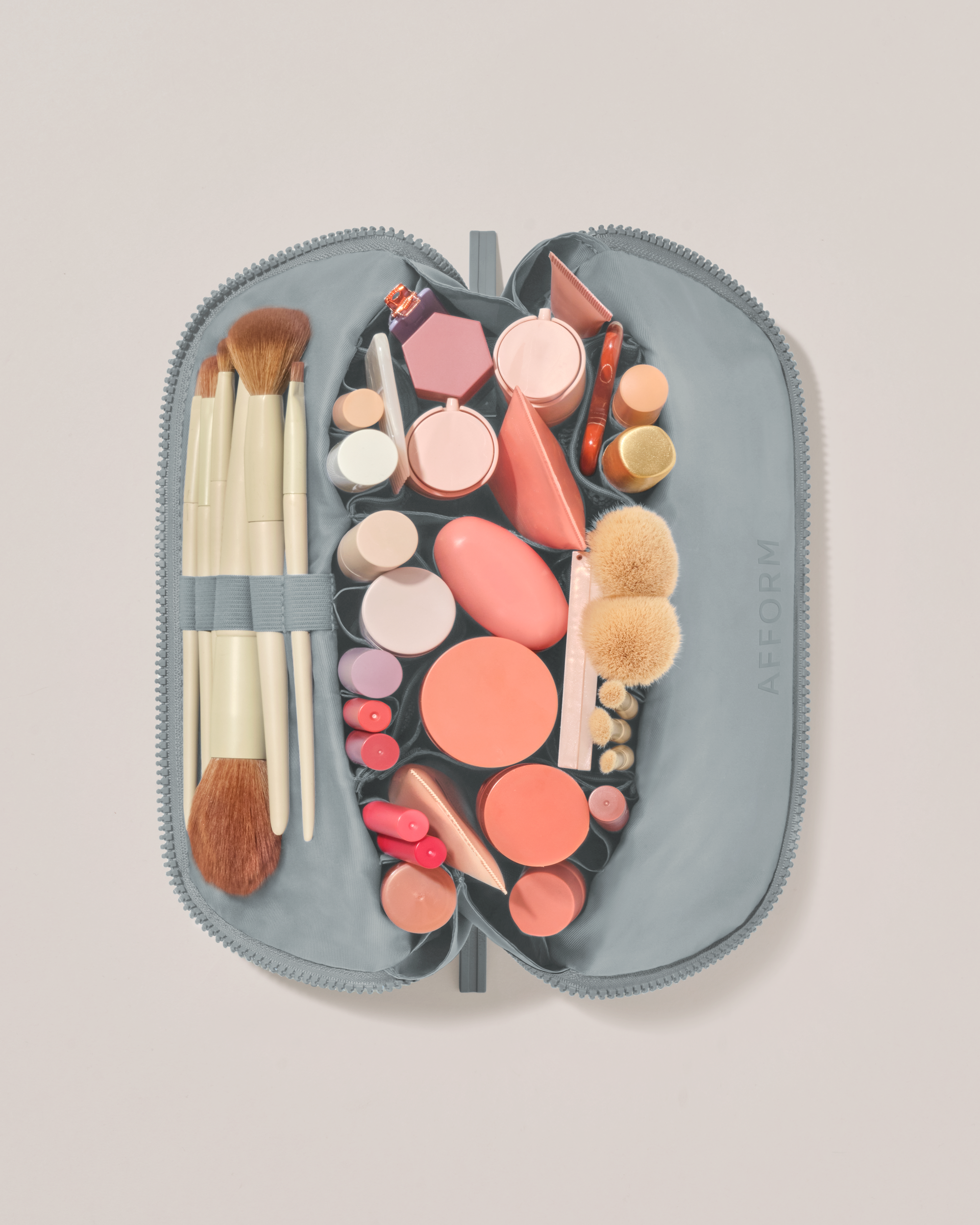 Overhead view of the Medium Slate (blue) Traveller makeup bag fully packed with upright beauty products and organized compartments