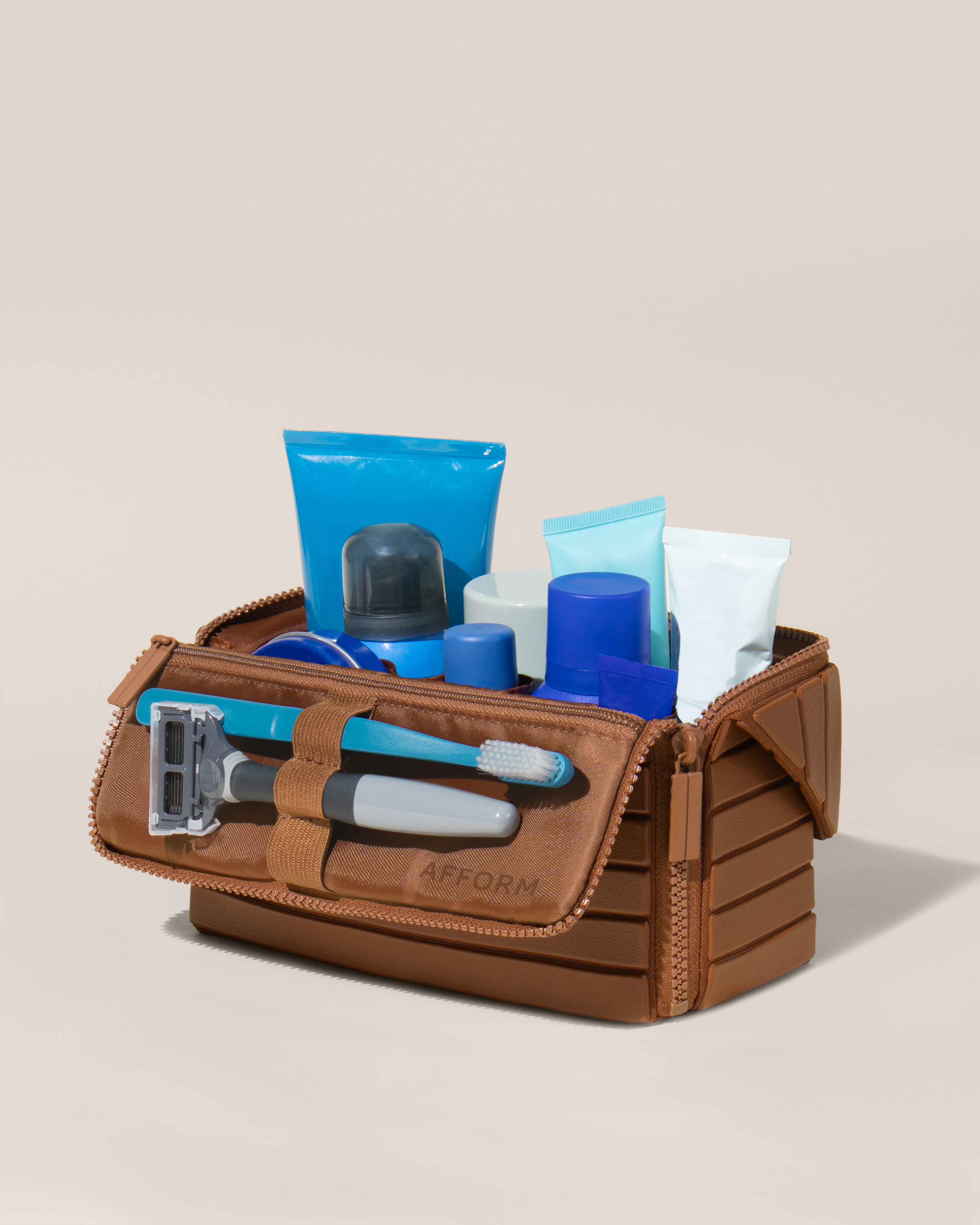 Open Afform Medium Vicuna (brown) Kit, shown open and packed with grooming essentials like razors, cologne, and skincare. A structured, travel-ready toiletry organizer