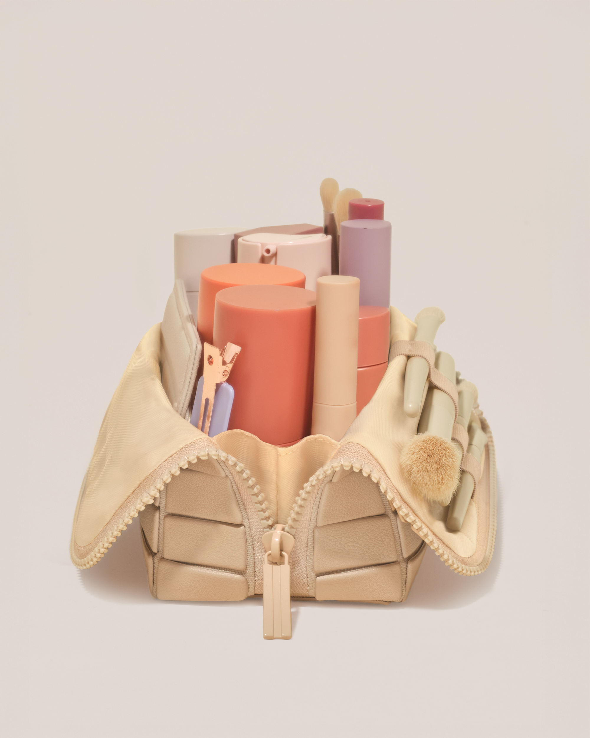 Side profile of the Small Bisque (white) Traveller makeup bag filled with beauty essentials standing upright, showing flexible compartment design
