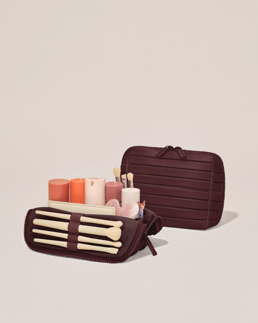Open and closed Afform Small Cassis (maroon) Traveller makeup bag showing skincare, brushes, and curated travel essentials