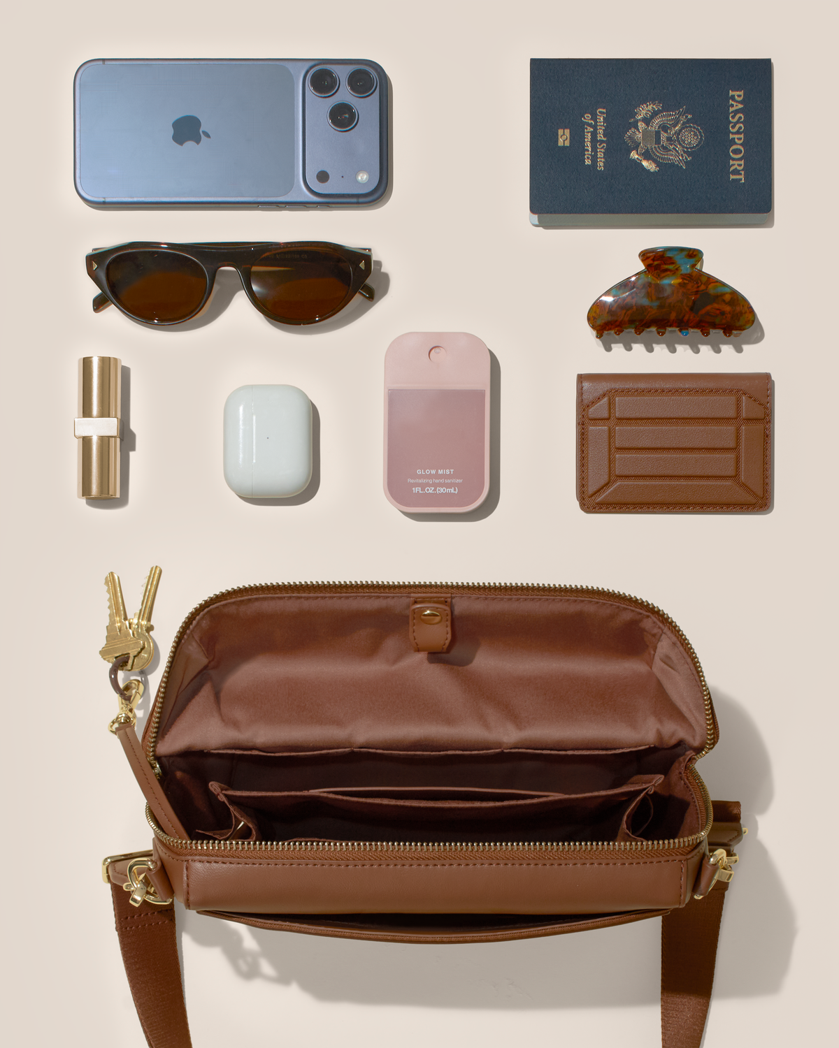 Overhead view of the open Vicuna Crossbody bag with phone, passport, sunglasses, card holder, and everyday essentials