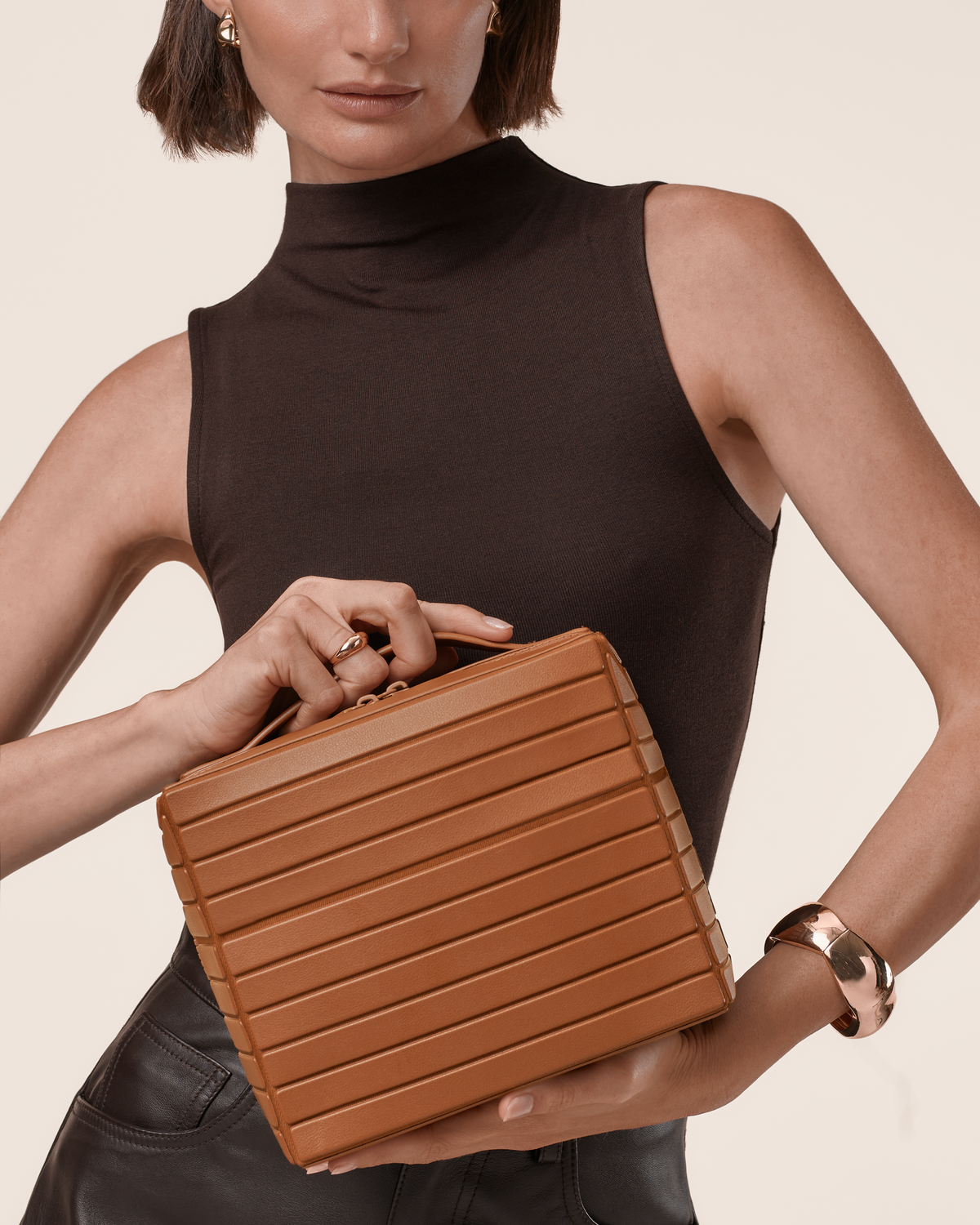 Model in a black sleeveless top holding the Afform Vicuna Kit by its top handle, showing the structured horizontal bar design