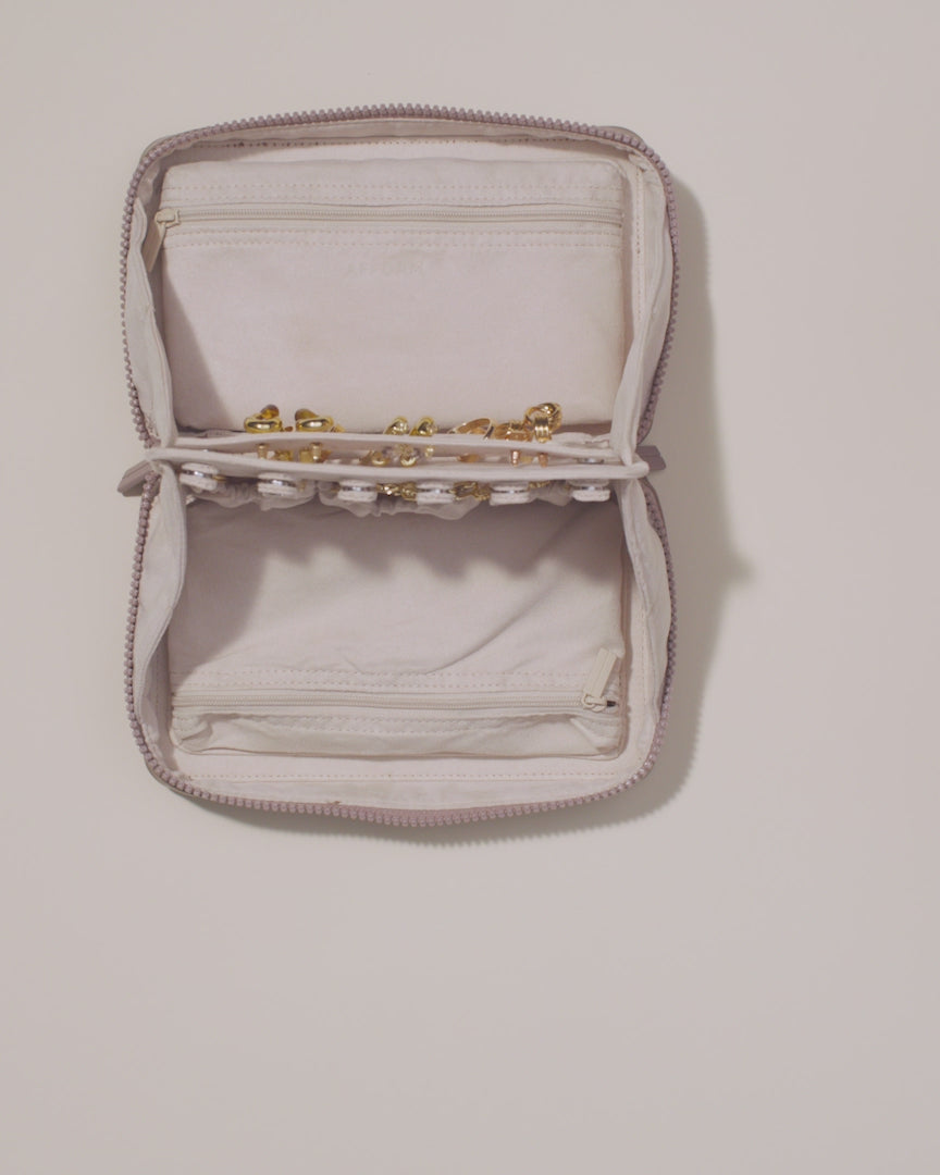 Large Vault shown with two-sided interior with one side for rings and earrings and the other for necklaces. The ring and earring bars are shown being removed. Jewelry is shown being packed and organized on the ring bar, earring bar, necklace pouches, and zipper pouches.